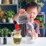 Happy little school kid studying science, making DIY Lava Lamp Science Experiment with oil, water and food coloring, Kid-friendly fun and easy science experiments at home concept