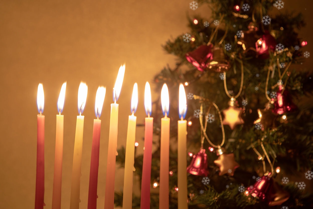 Lit menorah candles with a decorated Christmas tree in the background, featuring red ornaments and festive lights. Snowflake patterns overlay the scene.