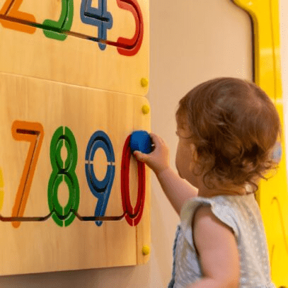 A child using a colourful toy on a wall.