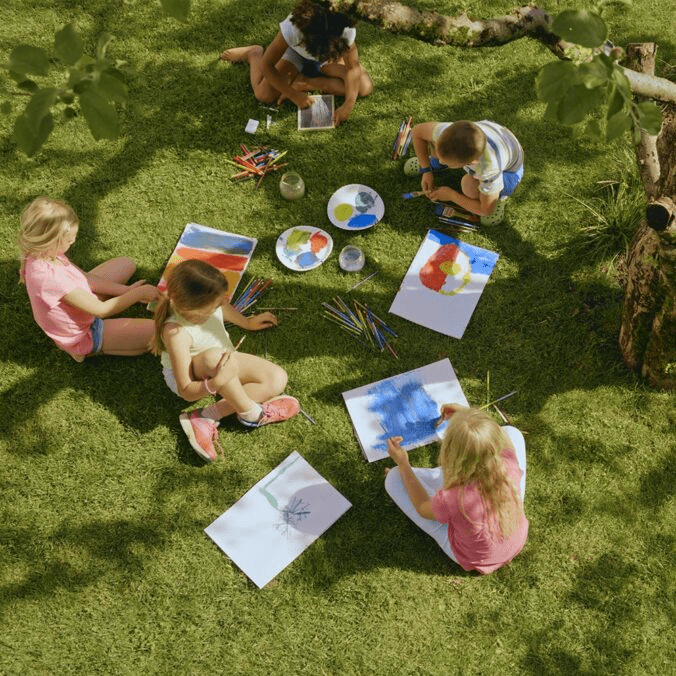Children doing art on a lawn.